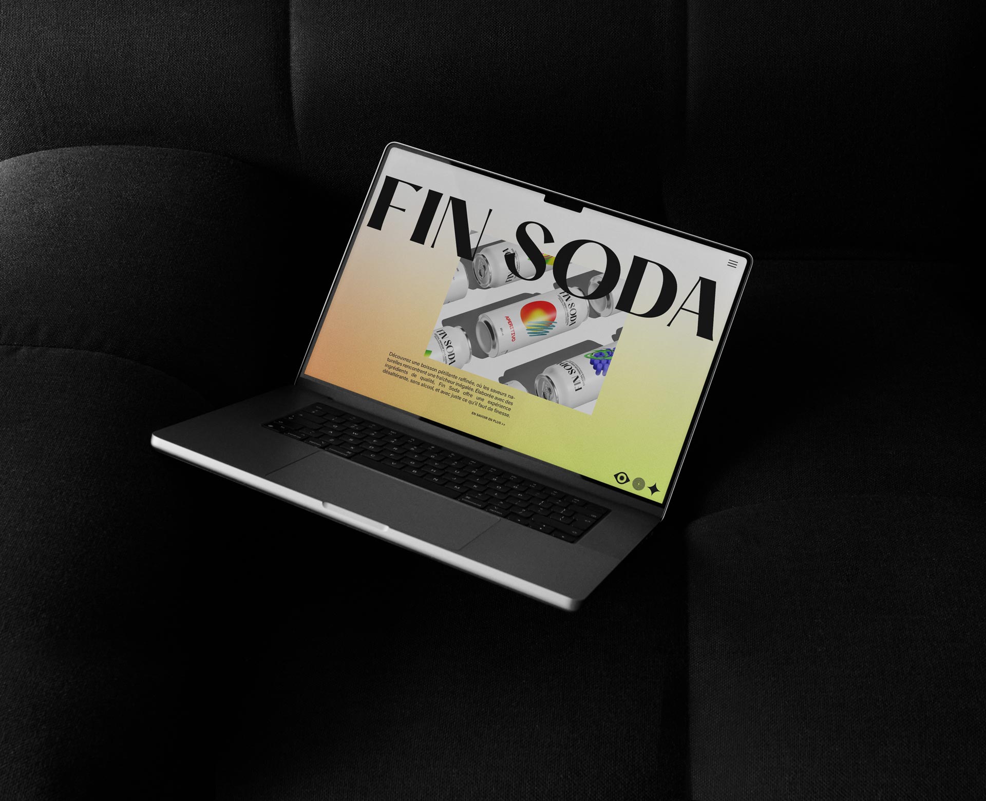 MacBook posé sur un canapé noir, affichant le site web de 