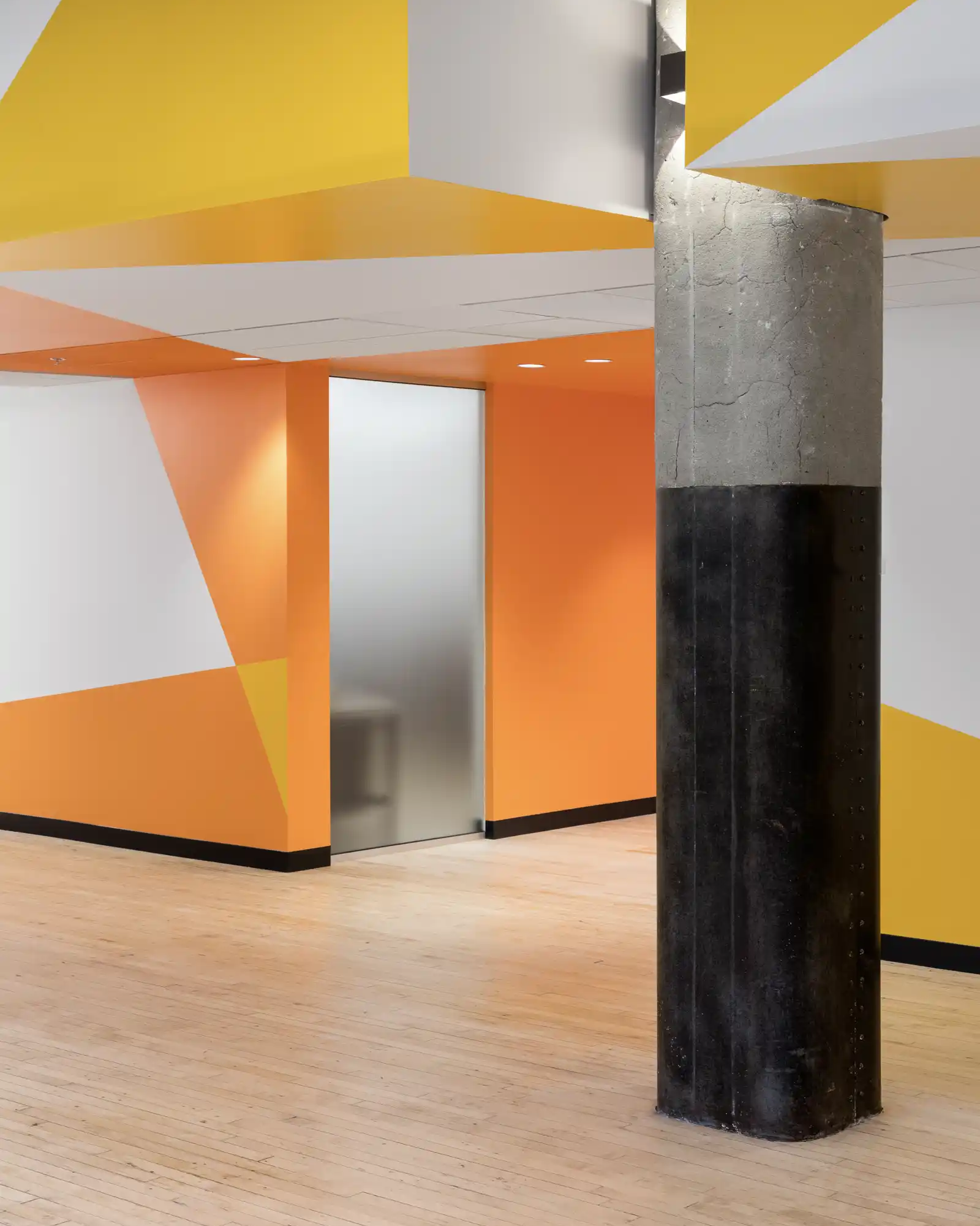 Murale géométrique orange et jaune dans un espace de bureaux.