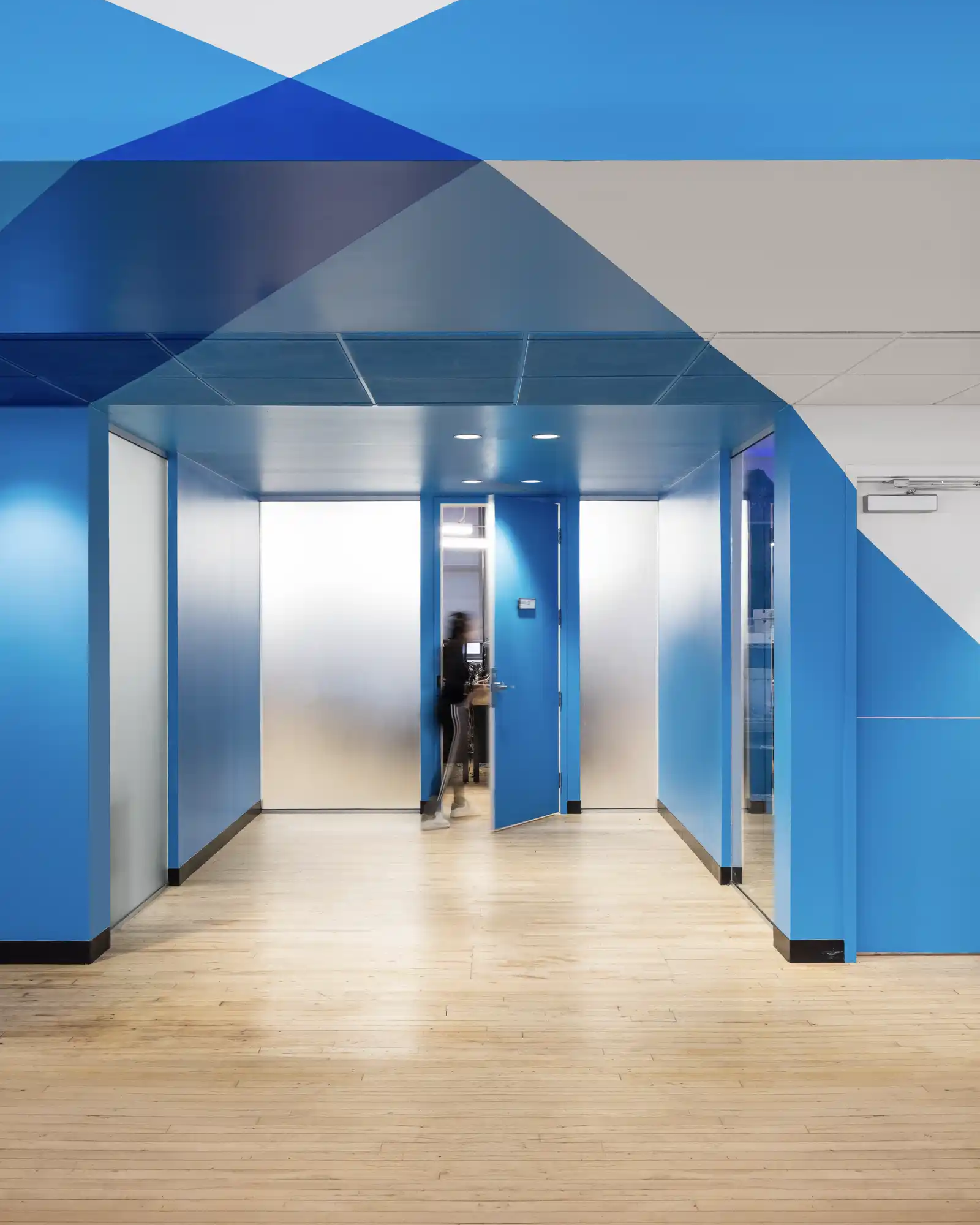 Vue d’un corridor aux teintes vives avec une porte en verre dépoli.